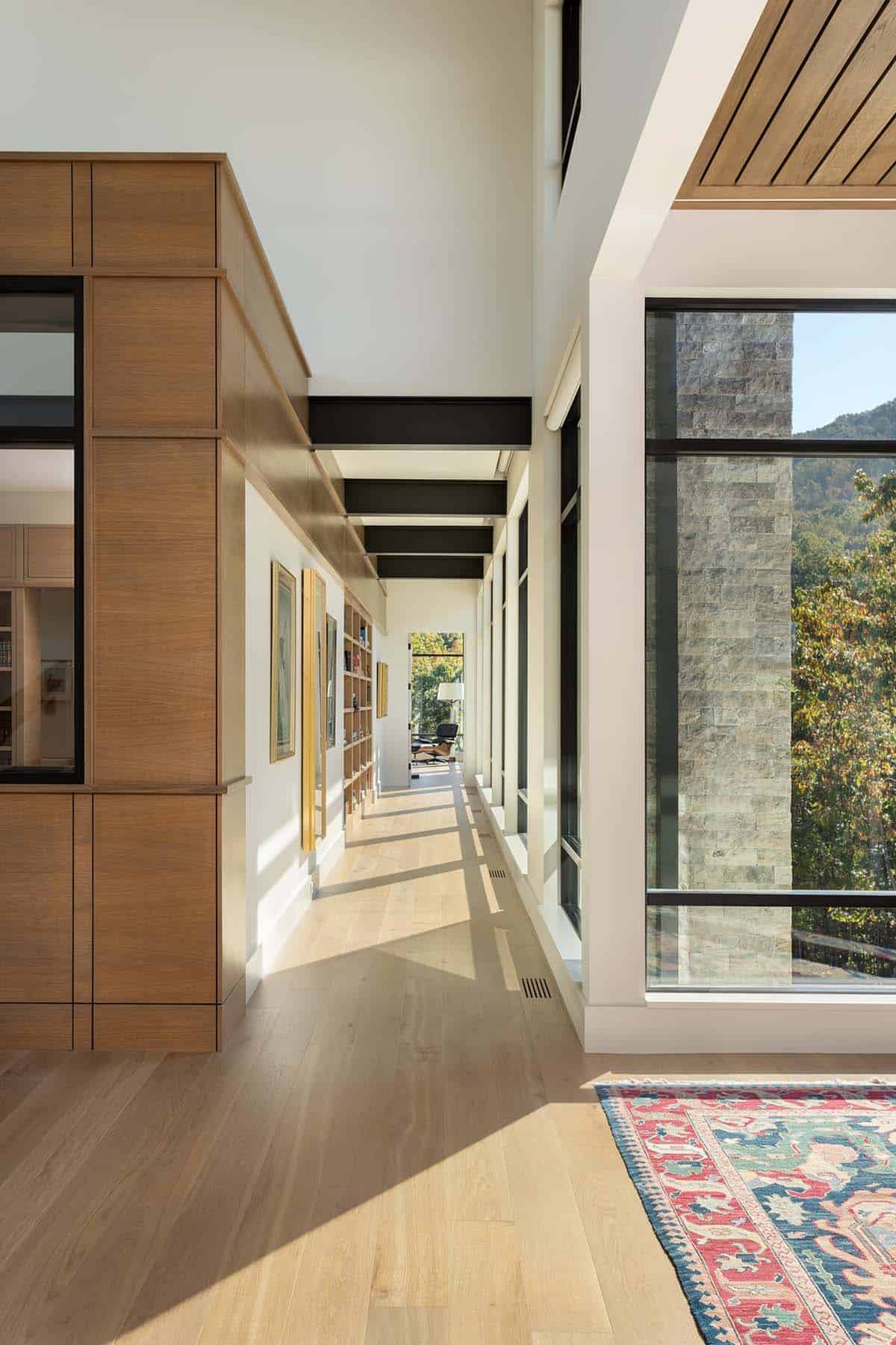 Sun-drenched hallway with wood built-ins, floor-to-ceiling windows, and mountain views