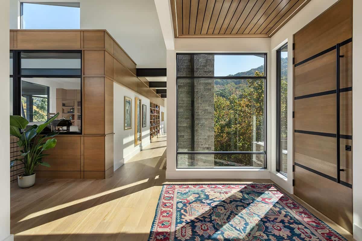 Entry hall with wood paneled walls, gallery corridor, and mountain views through glass
