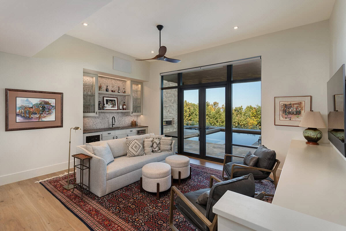Living room with built-in bar, gray sofa, and glass doors opening to pool terrace