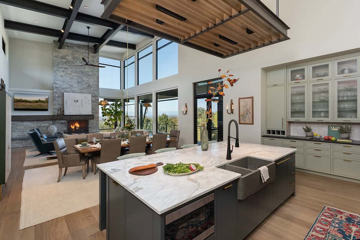 Open-plan kitchen and living area with marble island, wood ceiling, and mountain views