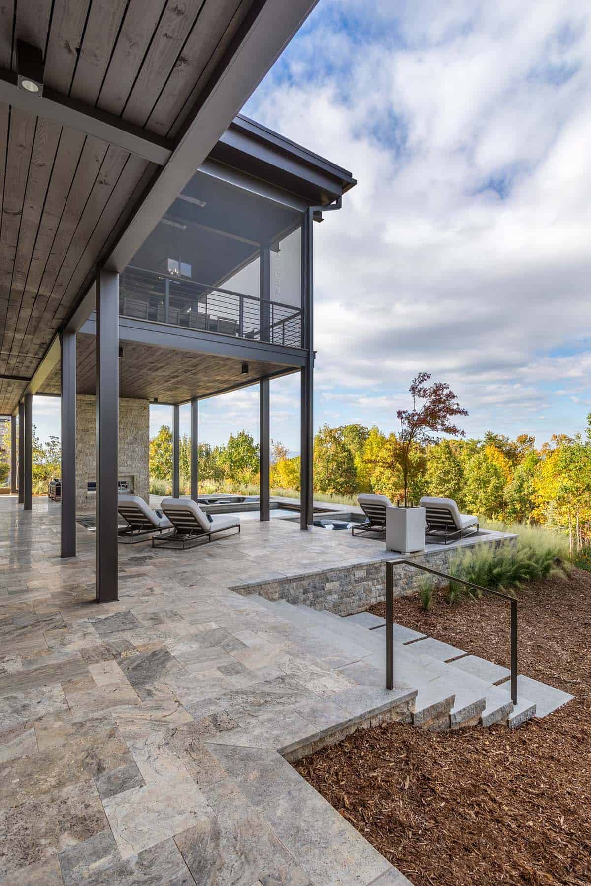 Lower terrace with lounge chairs, travertine paving, and steel column structure