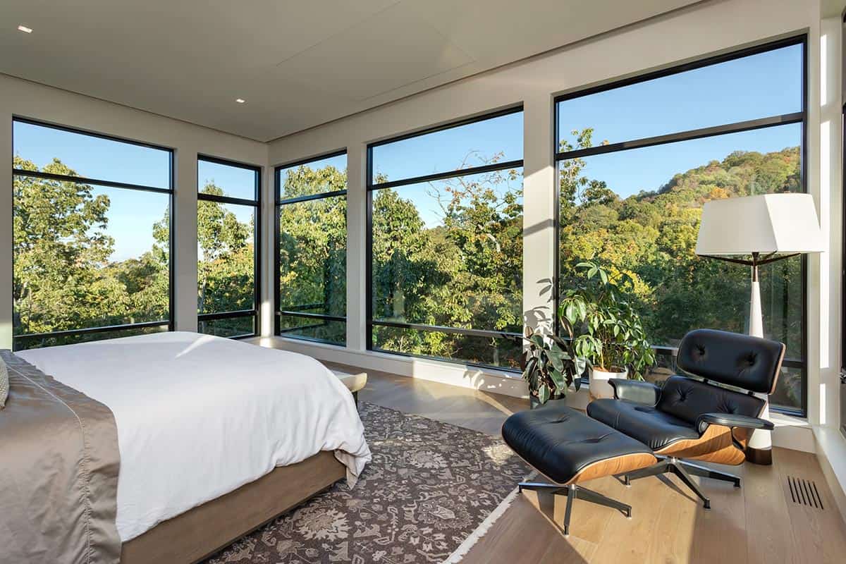 Primary bedroom with wraparound floor-to-ceiling windows and Eames lounge chair