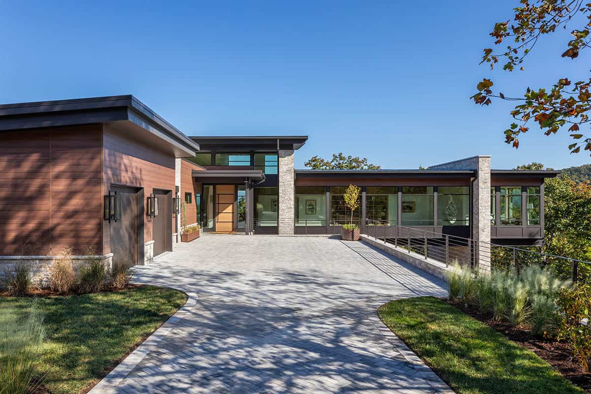 Modern home front approach with paver walkway, wood siding, and stone columns