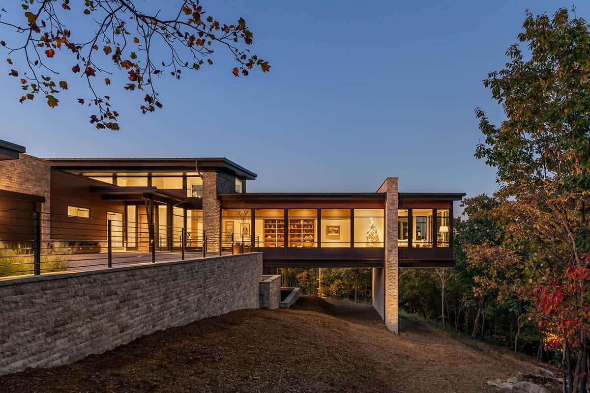 Illuminated cantilevered library wing at dusk above stone retaining wall
