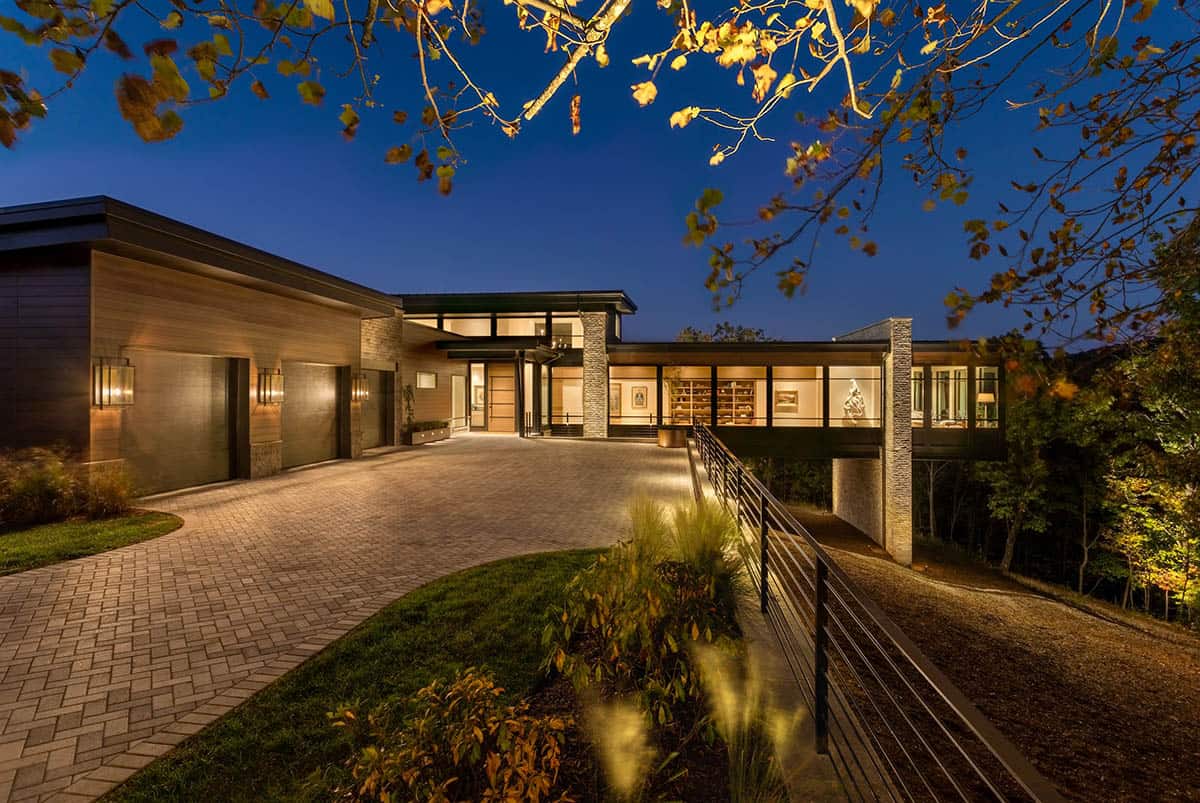 Illuminated modern home front elevation at night with paver driveway and landscape lighting