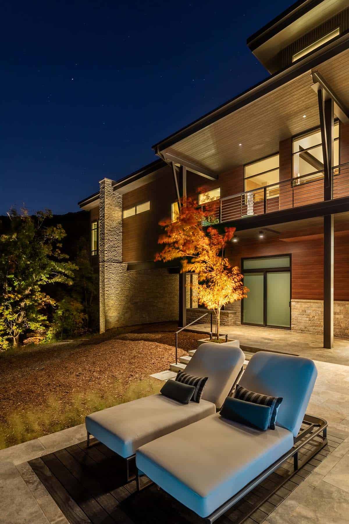 Pool terrace lounge chairs at night with illuminated Japanese maple and upper balcony