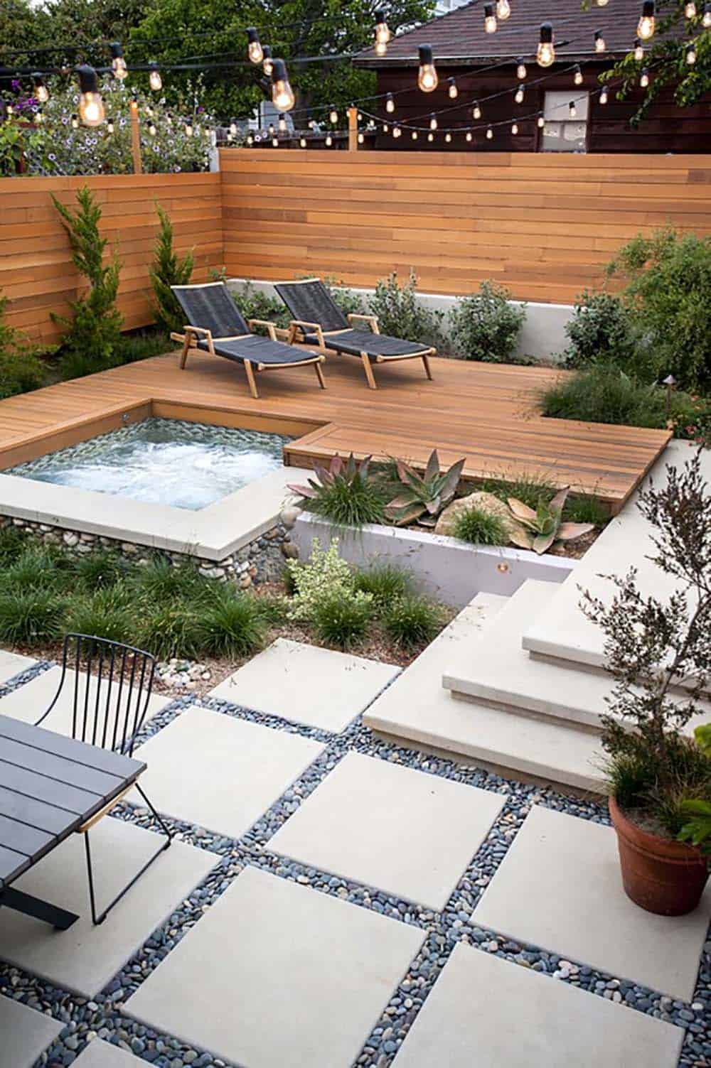 A sunken hot tub built into a cedar deck with chaise lounges, tiered concrete pavers, and a privacy hedge in Santa Monica, California