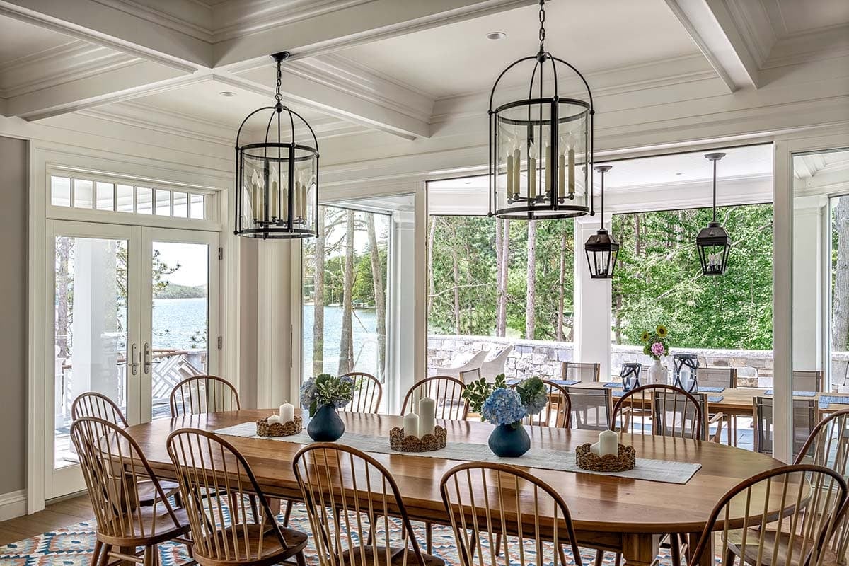 Dining room with oval wood table, lantern pendants, and French doors opening to lake views
