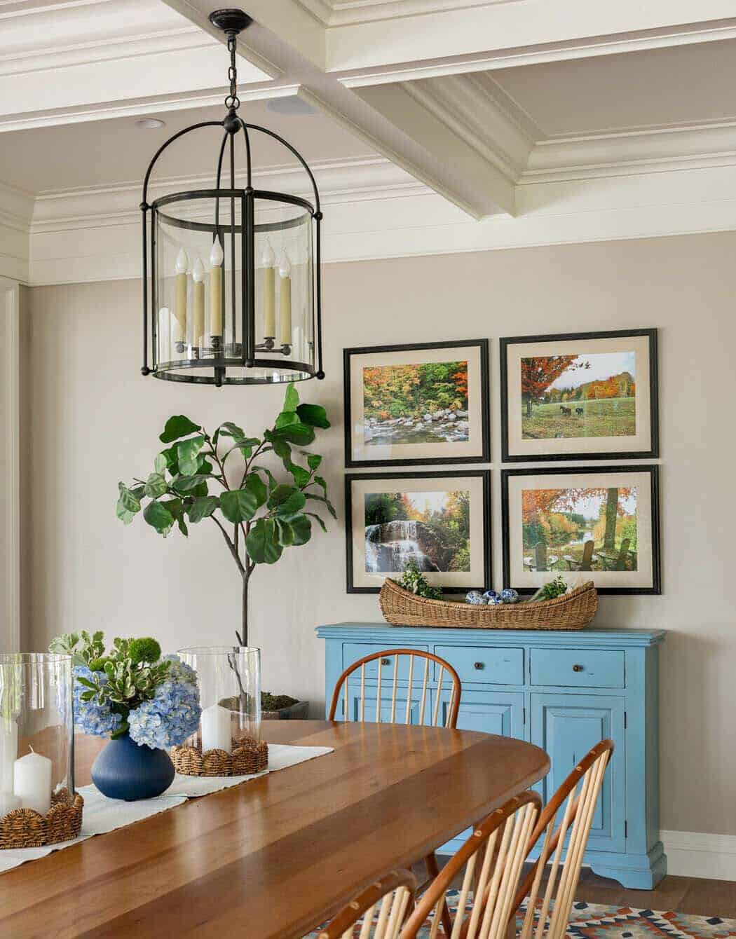 Dining nook with framed nature prints, blue sideboard, and lantern pendant light