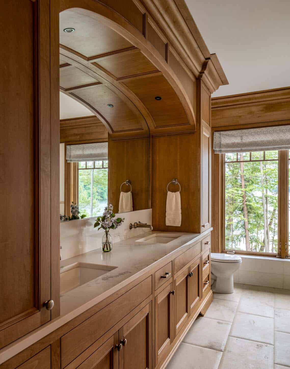 Wood-paneled bathroom with arched ceiling detail, double vanity, and lake-view window