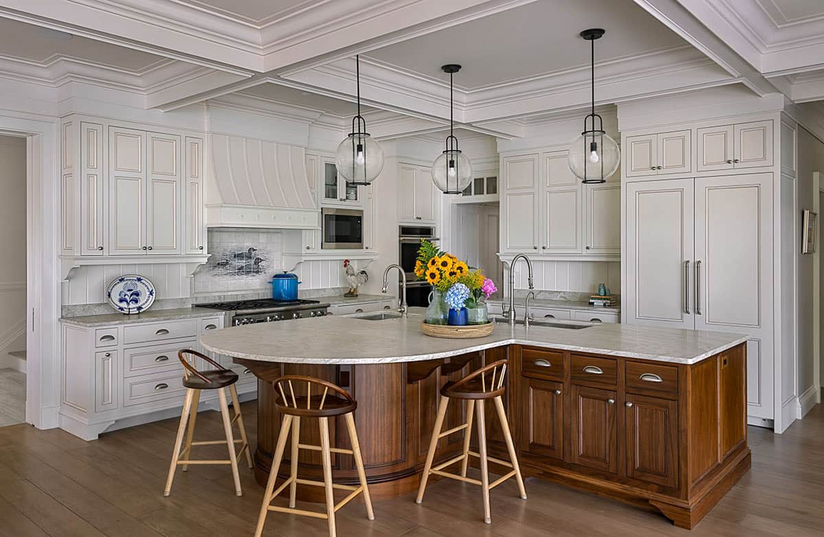 Kitchen with white cabinetry, dark wood island, glass pendant lights, and coffered ceiling