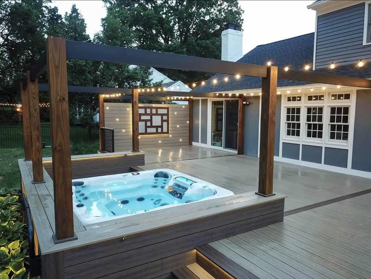 A built-in hot tub under a wood pergola with string lights and LED deck accents on a modern New Jersey patio
