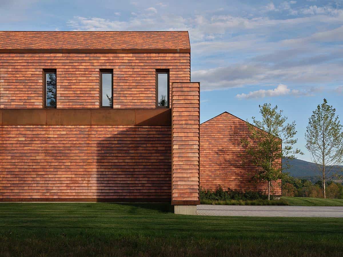 Close-up of cedar shingle cladding with Corten steel band and secondary gabled outbuilding