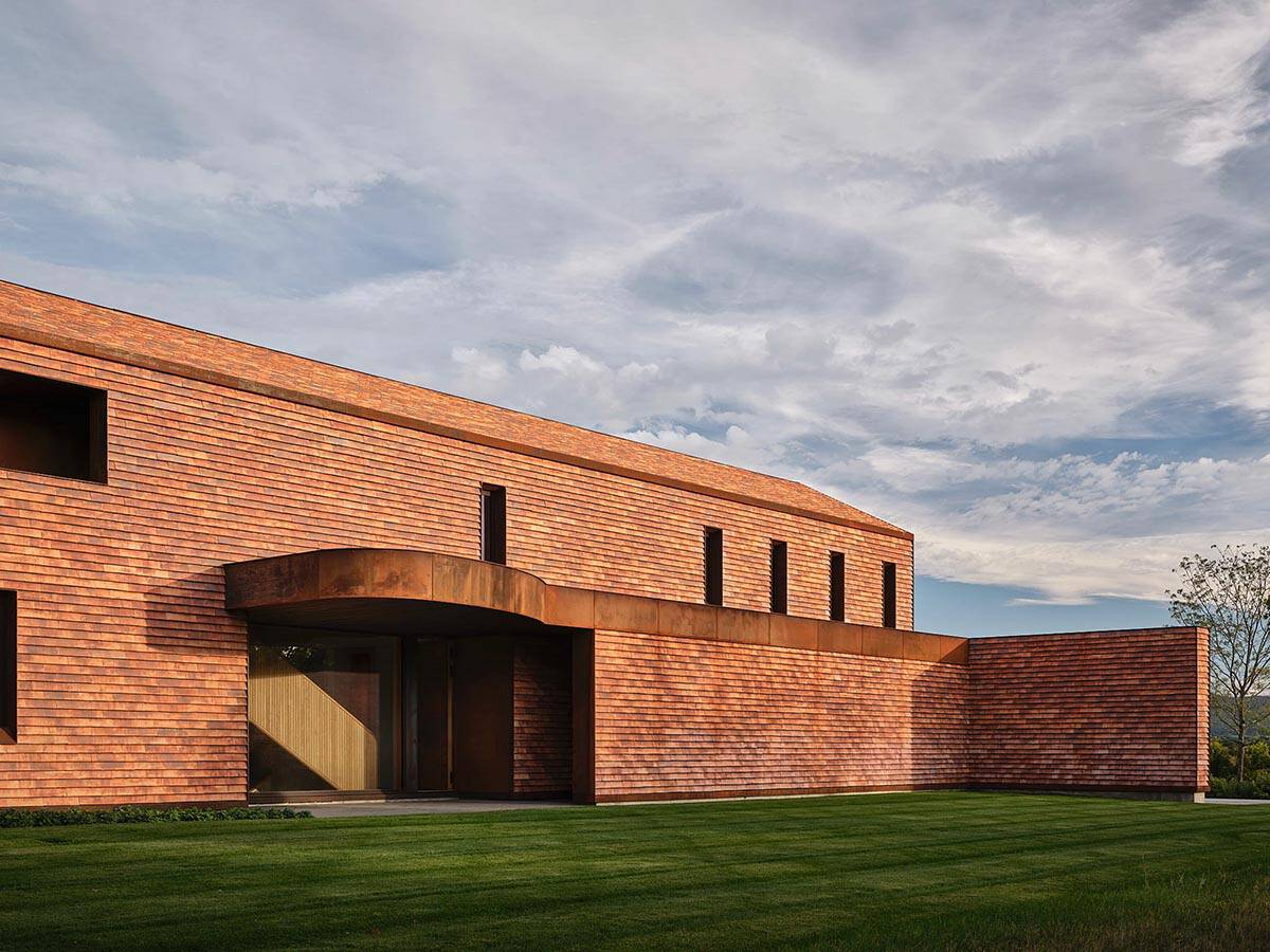Front entry canopy with curved Corten steel detail on cedar-clad two-story home
