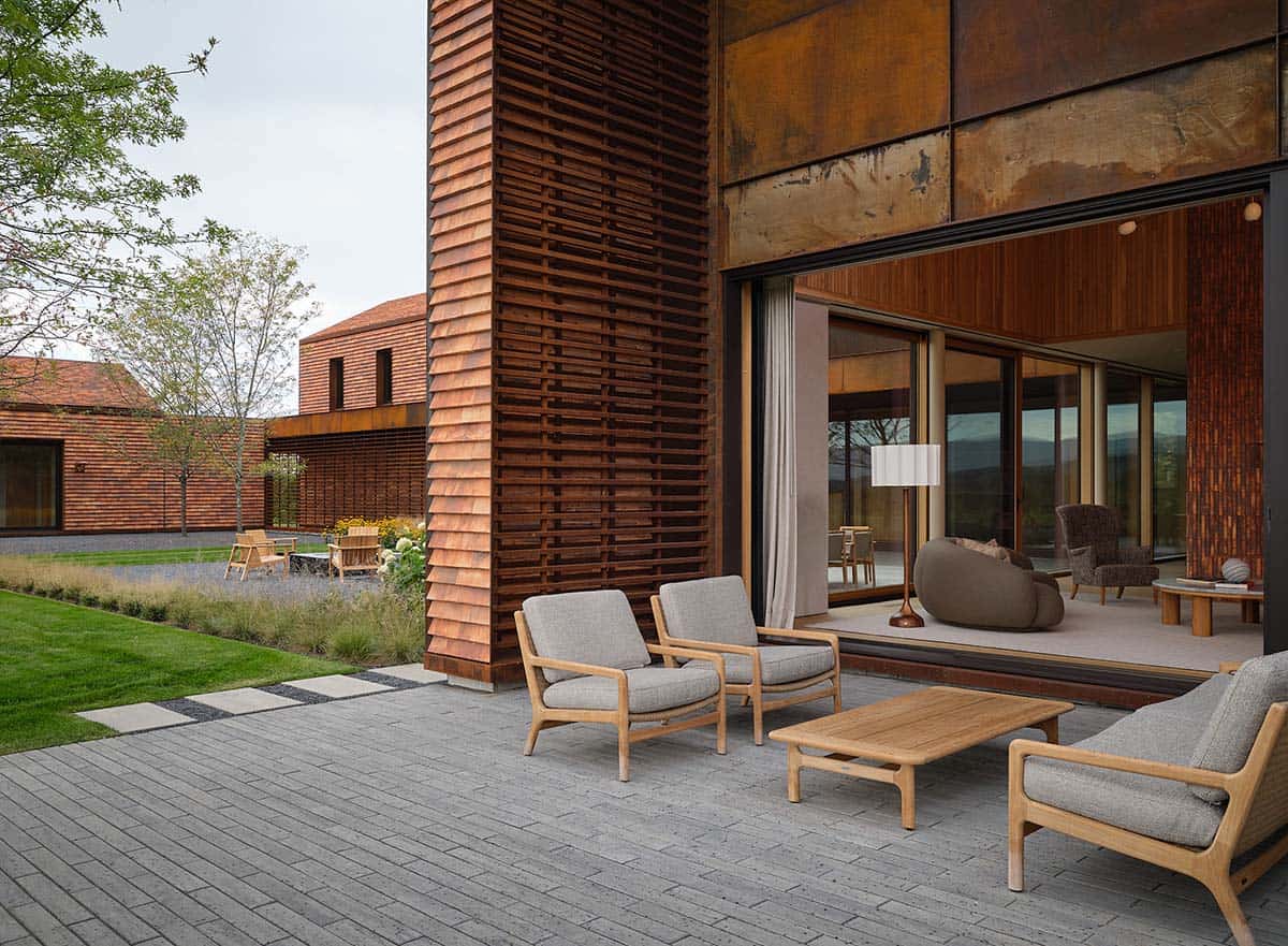 Courtyard patio with teak lounge furniture, cedar louvers, and weathered steel cladding