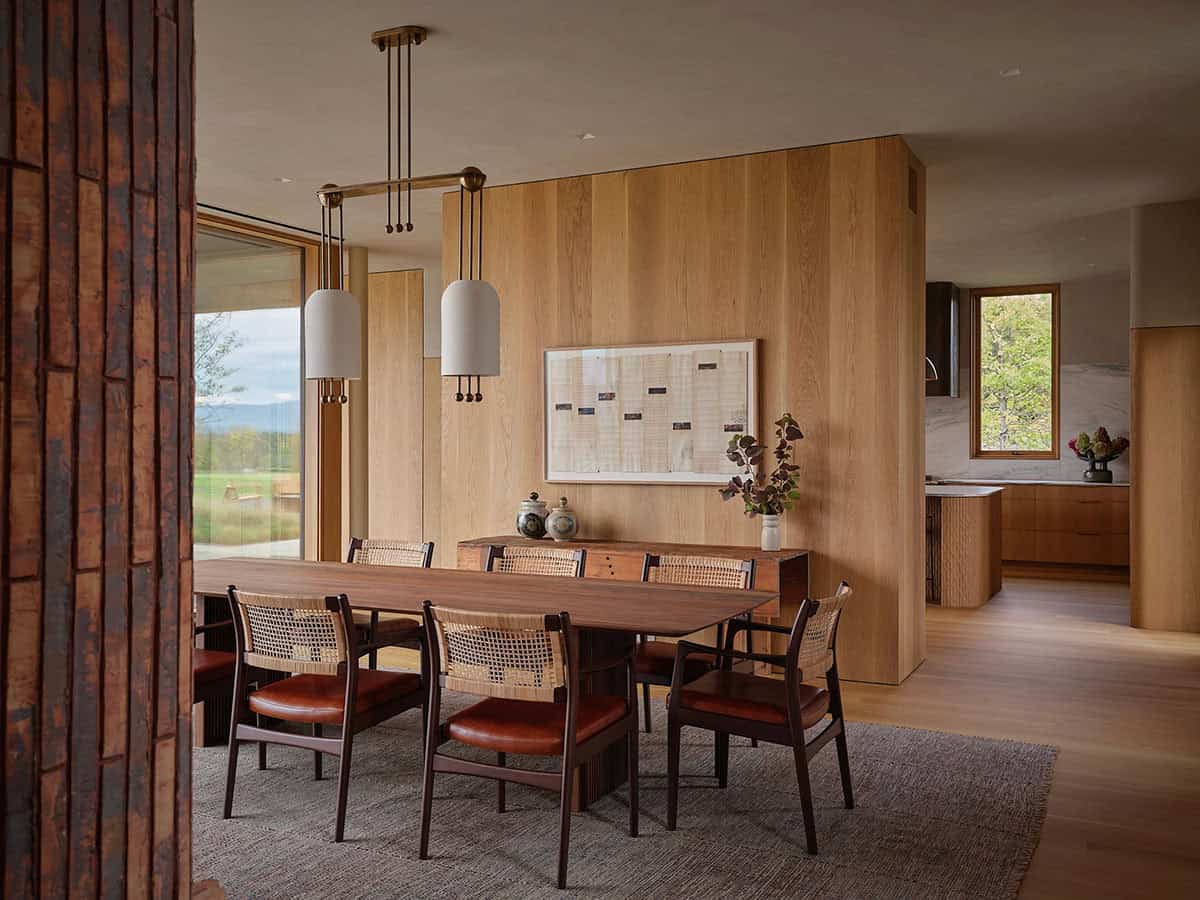 Dining room with walnut table, cane chairs, oak paneling, and brass pendant lights