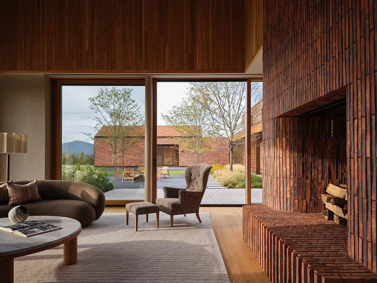 Living room with curved sofa, wood-fired brick fireplace, and courtyard views