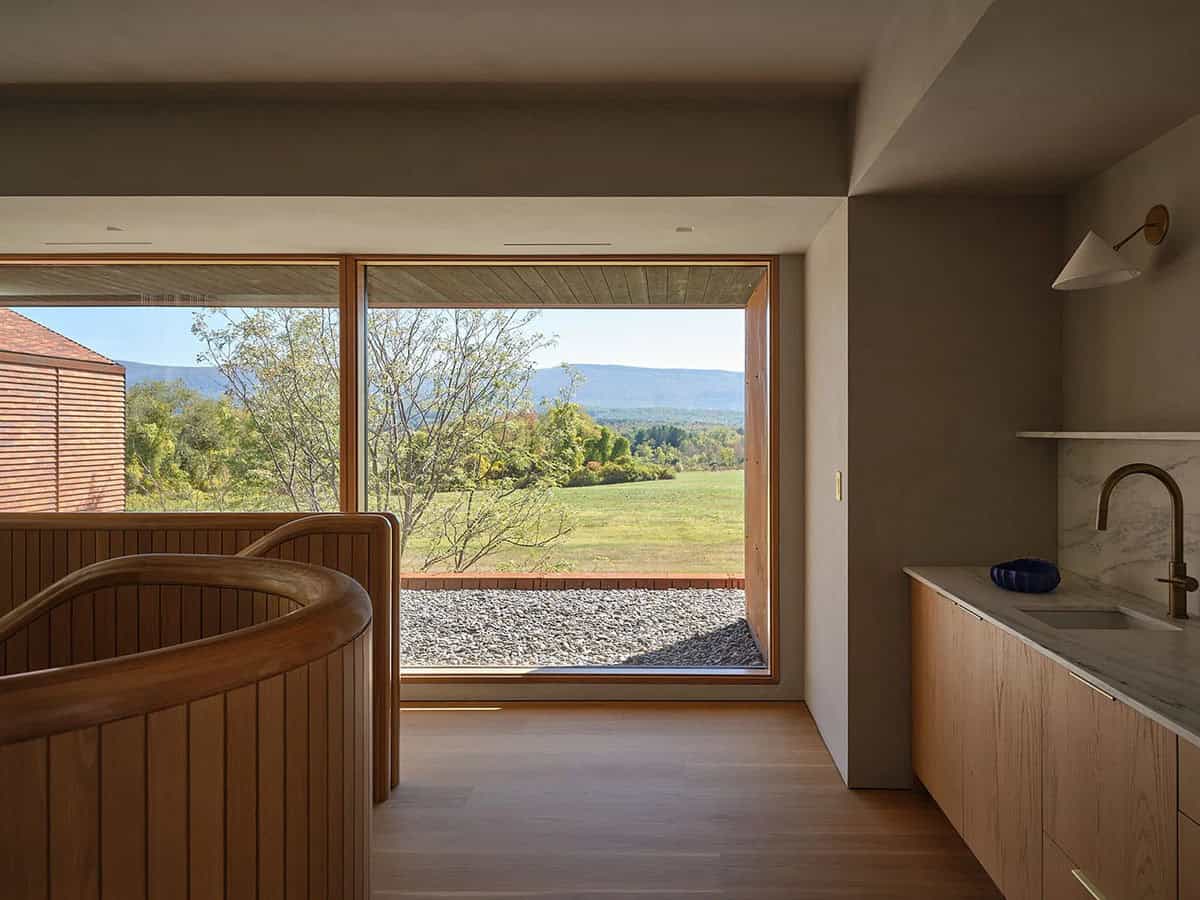 Upper-level landing with curved wood stair railing and panoramic Vermont mountain views