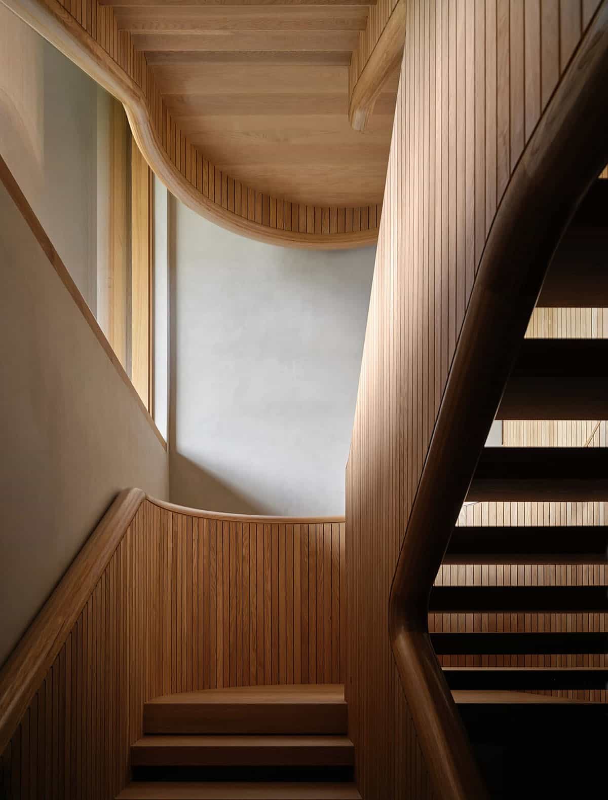 Sculptural oak staircase with curved slatted balustrade and plastered curved wall