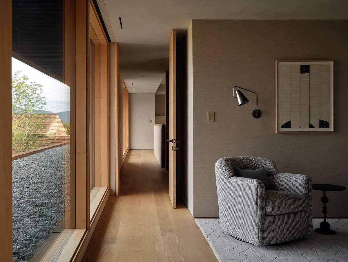 Upper hallway with floor-to-ceiling windows overlooking a gravel garden and cedar rooftops