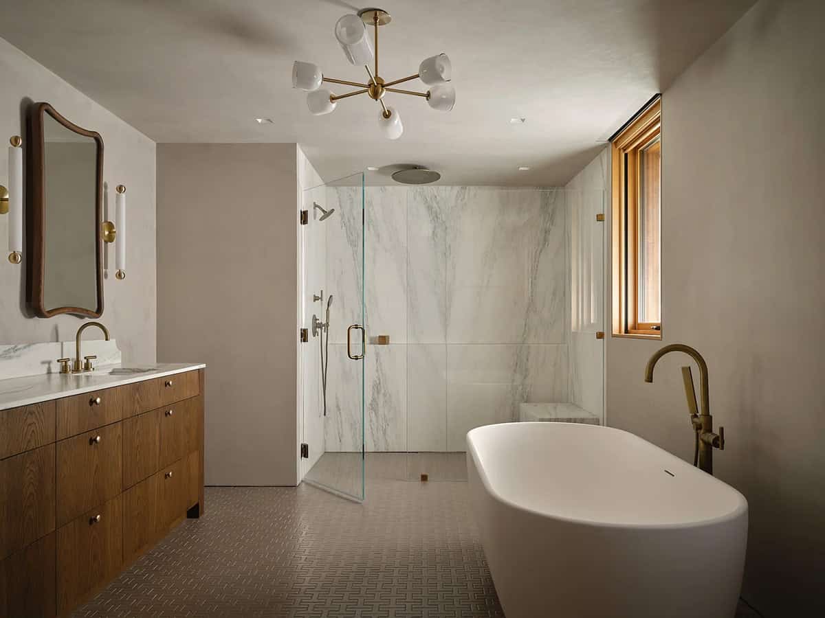 Primary bathroom with freestanding soaking tub, marble shower, walnut vanity, and brass Sputnik chandelier