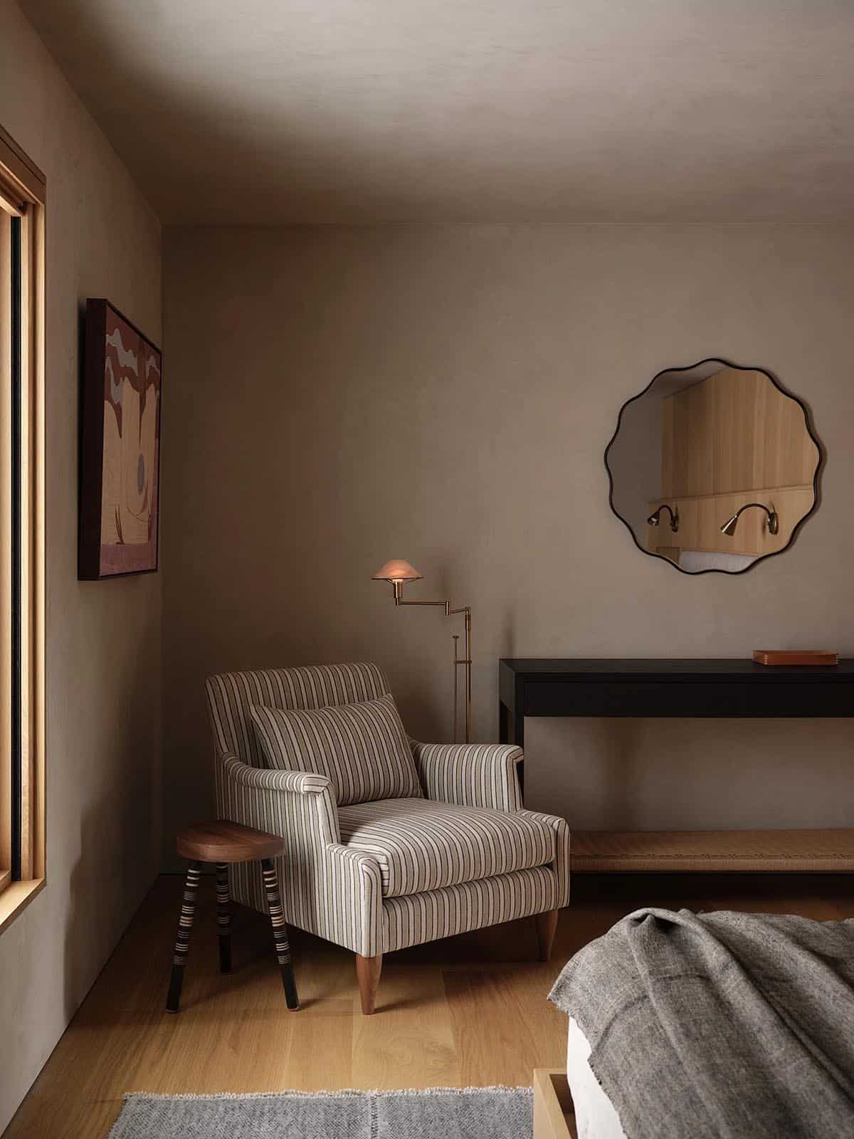 Bedroom corner with striped armchair, wavy mirror, brass floor lamp, and dark console table