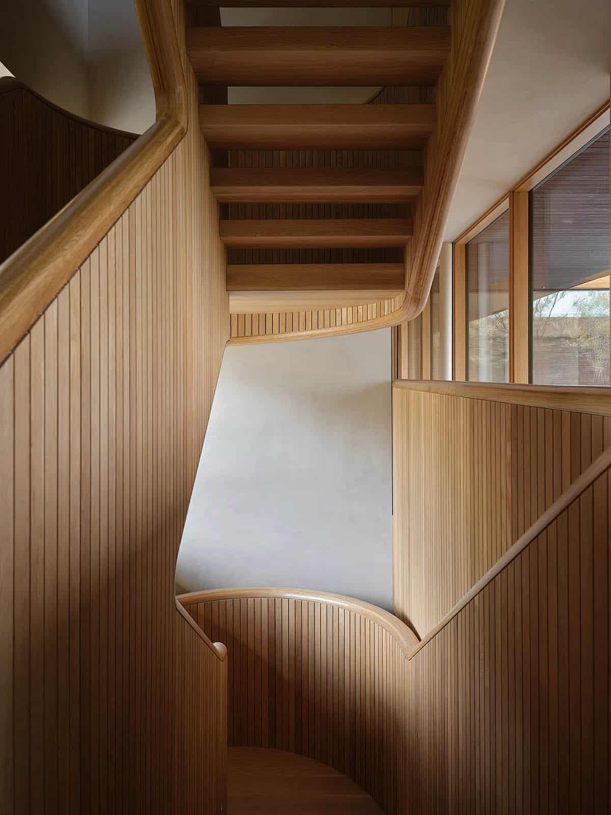 Overhead view of sculptural oak staircase with curved slatted balustrade and plastered stair well