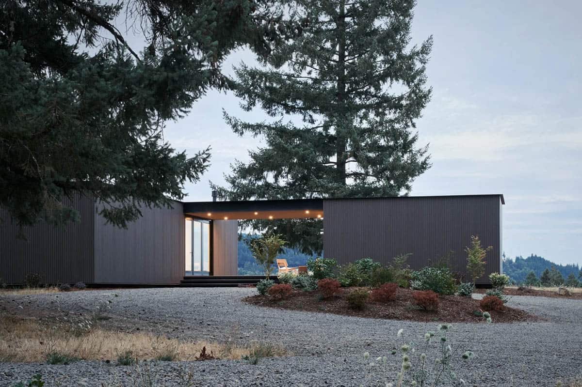 Dark house exterior with central breezeway opening at dusk
