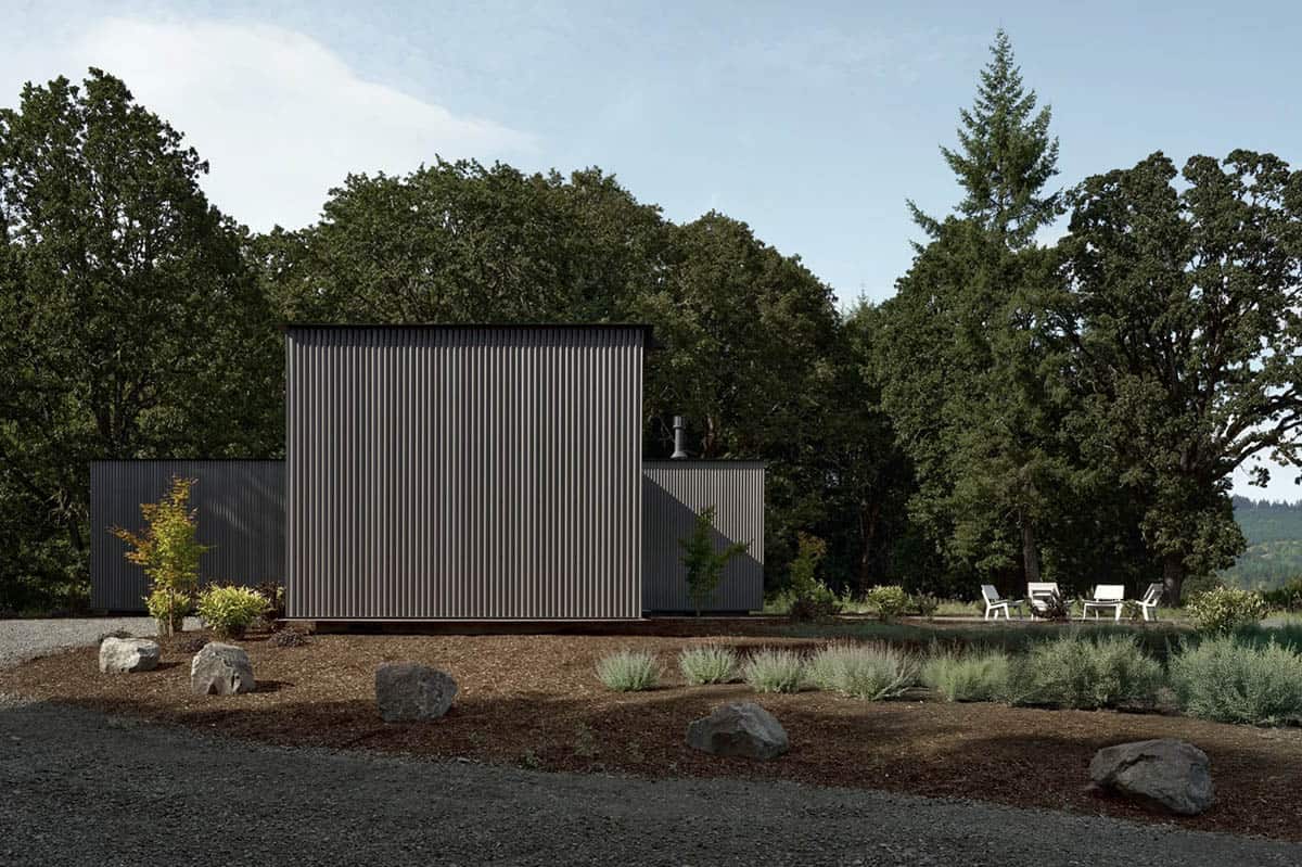 Corrugated metal volume of the house framed by oak trees