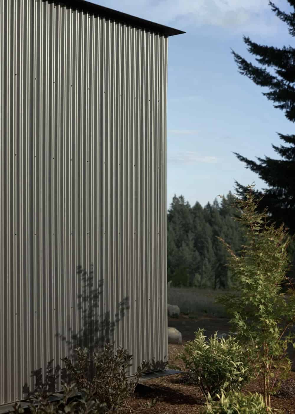 Detail of vertical corrugated metal siding against a pine forest
