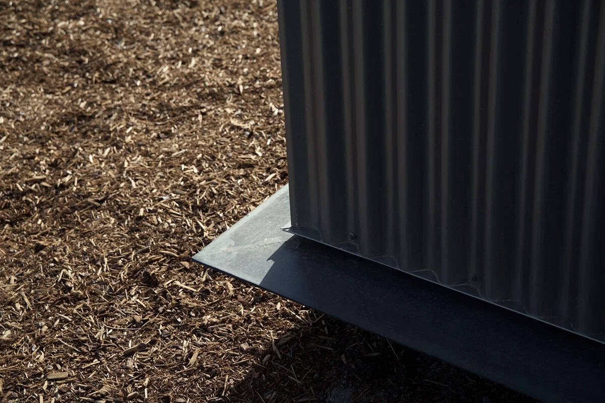 Close-up of corrugated metal siding meeting a concrete base