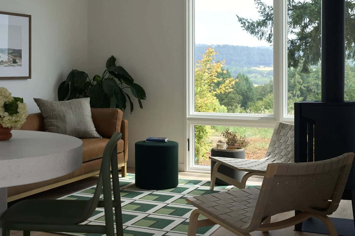 Living room corner with leather sofa, wood stove, and hillside view