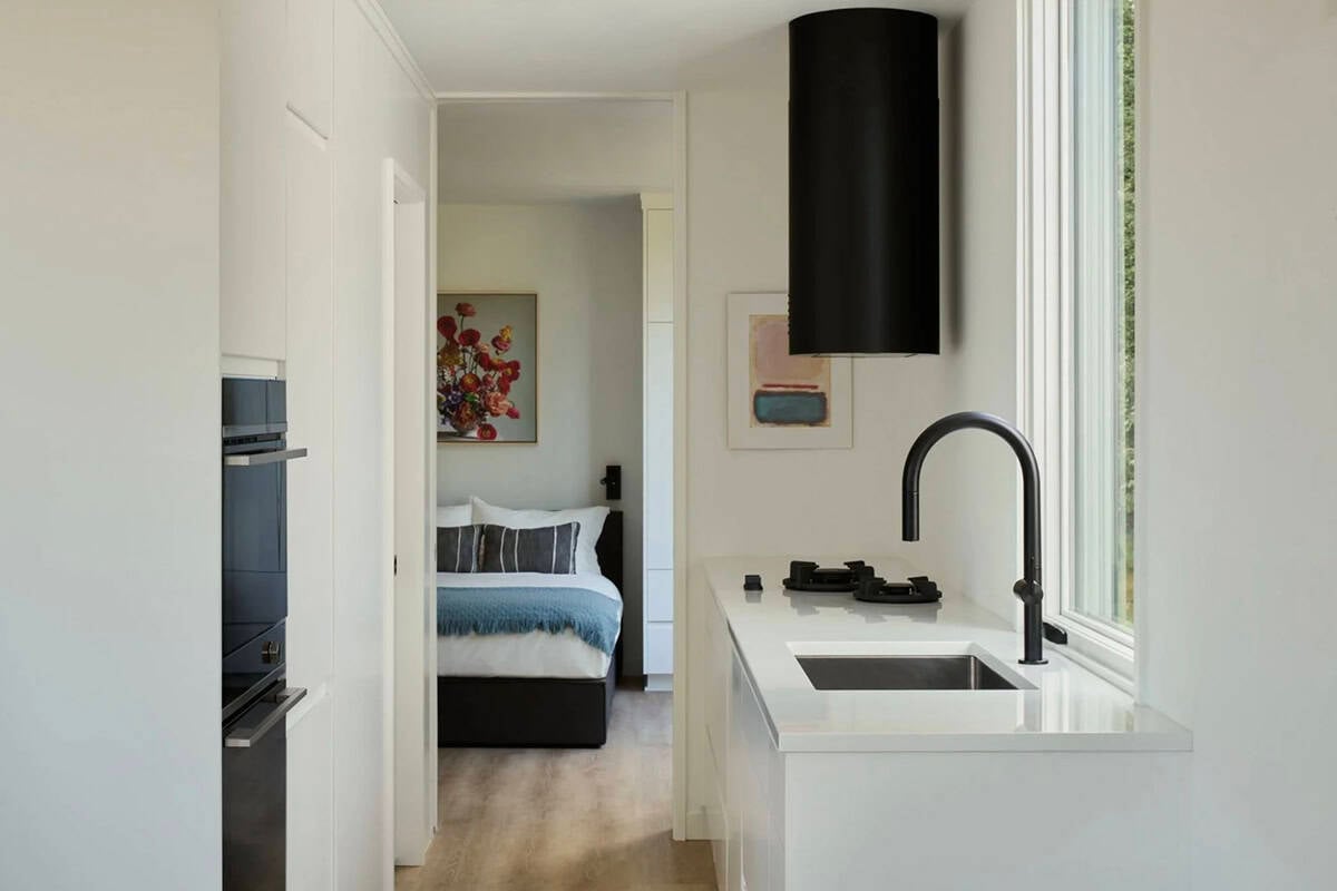 Galley kitchen view through to bedroom with floral artwork