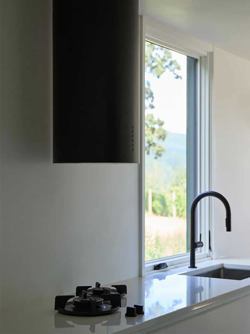 Kitchen sink and black faucet beside window with vineyard view