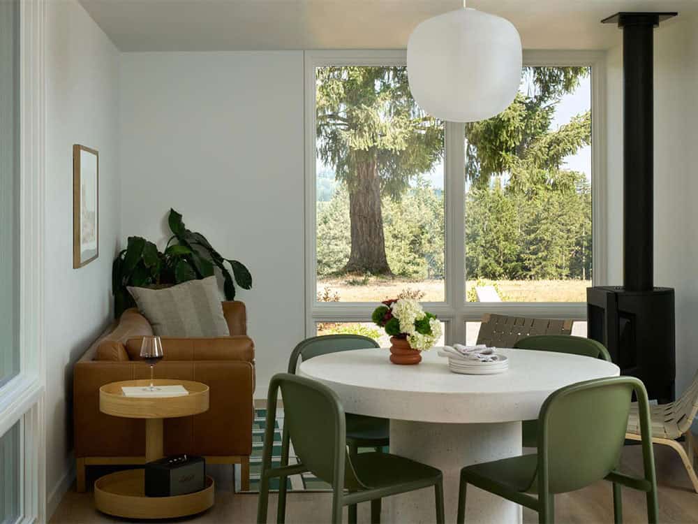 Dining nook with round table, green chairs, and wood stove