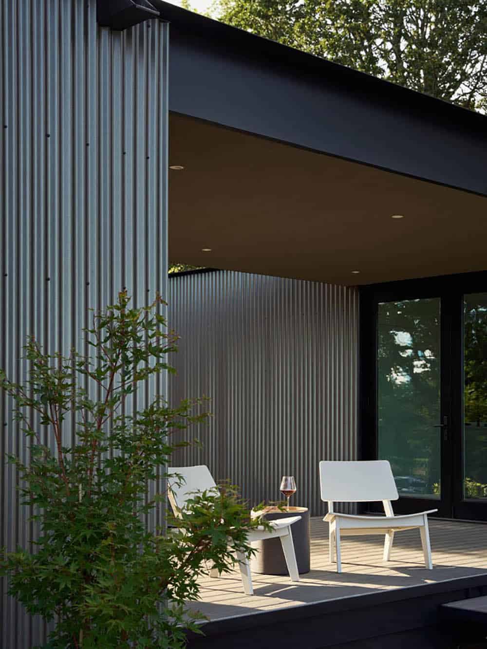Covered deck corner with white lounge chairs and glass doors