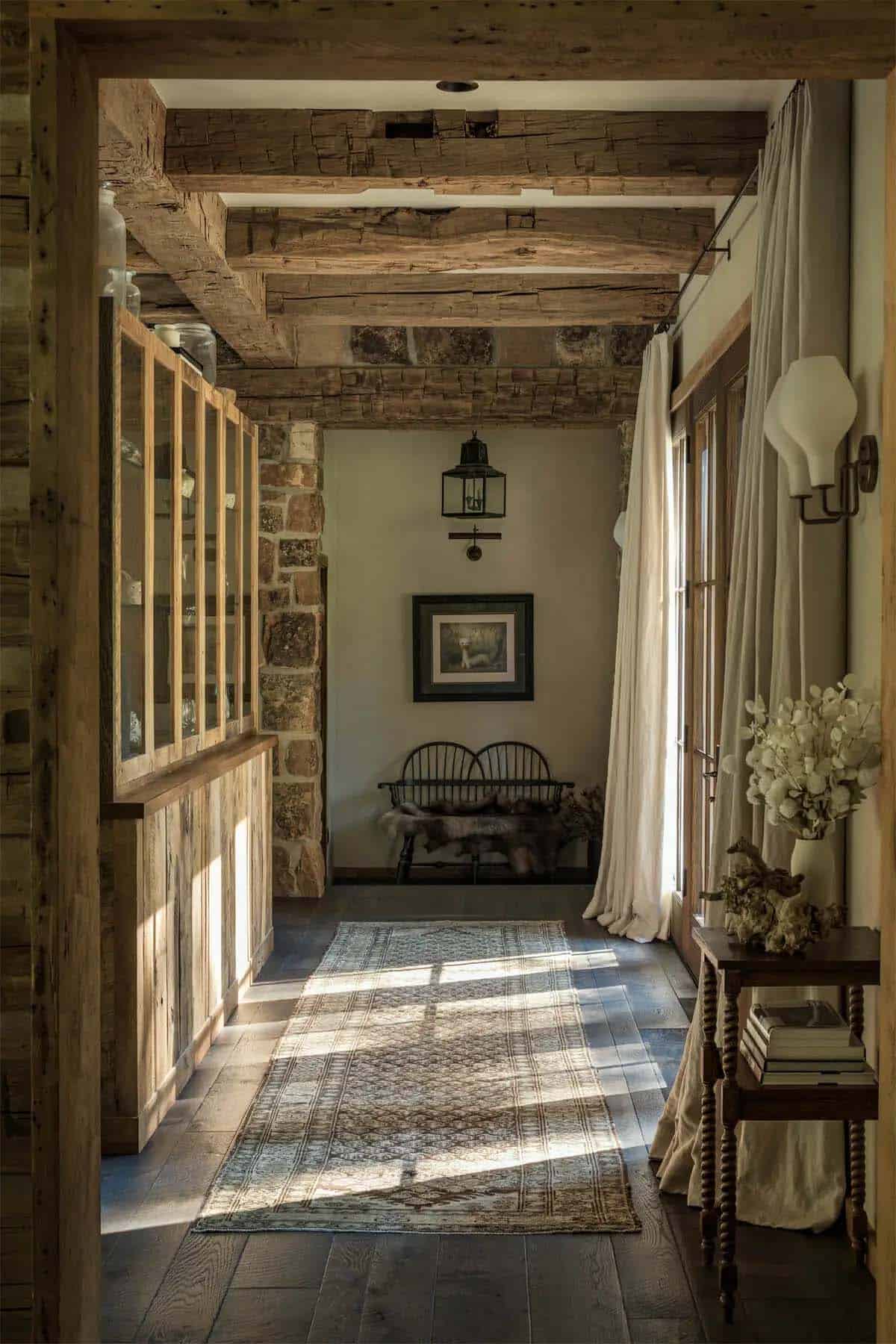 Hallway with reclaimed wood beams, stone column, and antique bench
