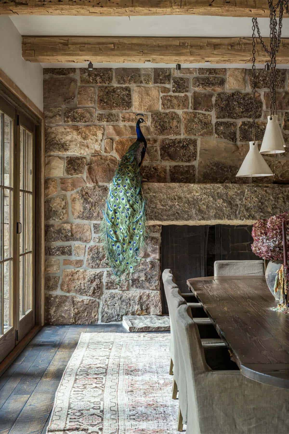 Taxidermy peacock mounted on stone fireplace wall in rustic dining room