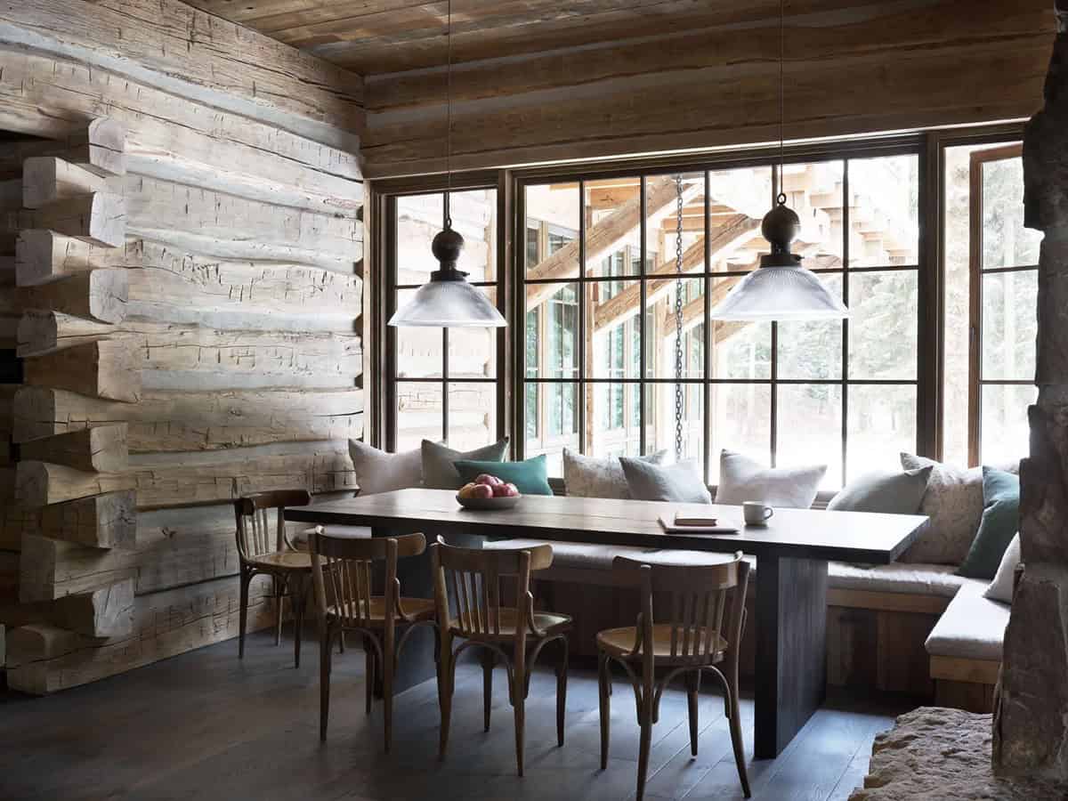 Dining nook with log wall, built-in bench, and glass pendant lights