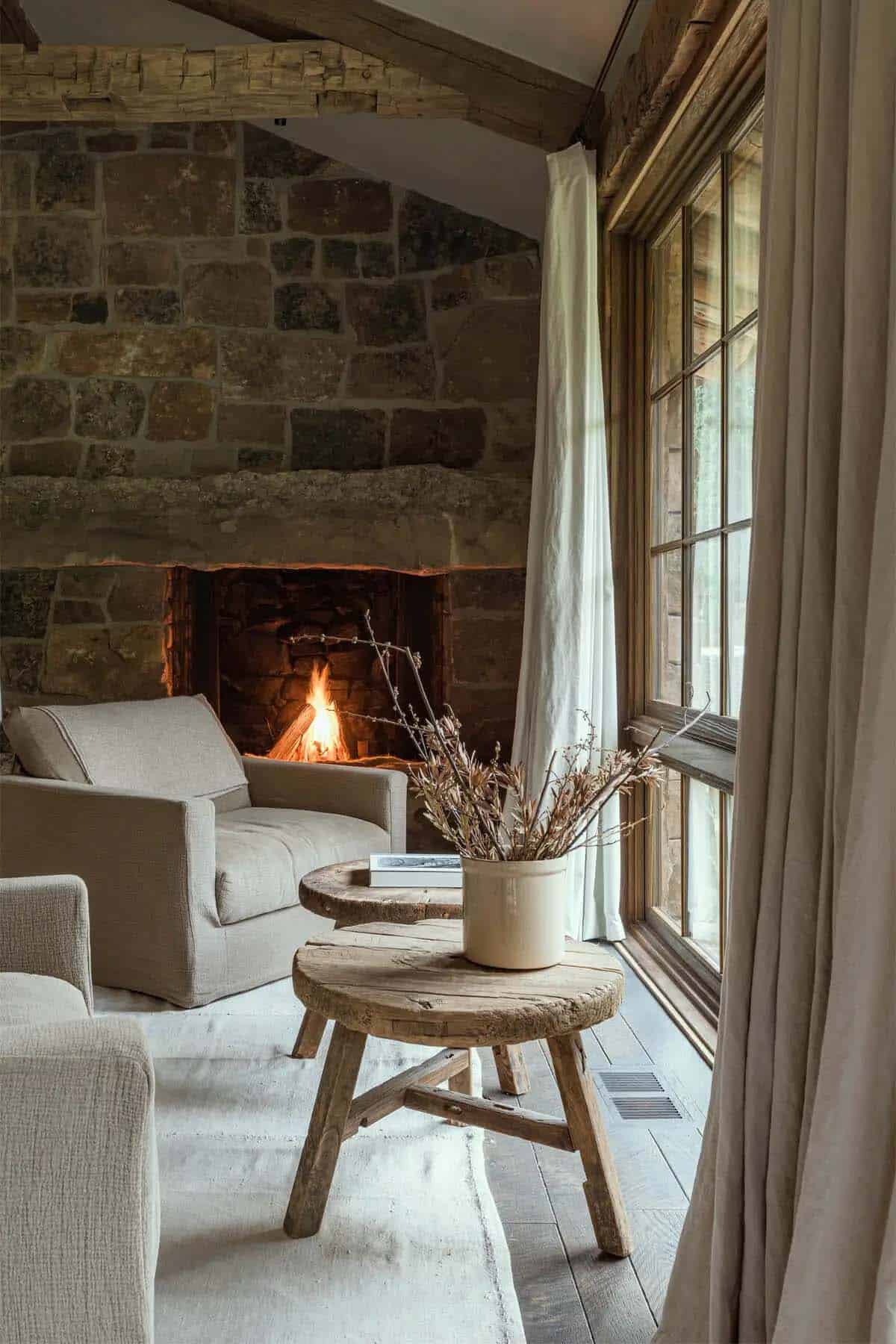 Cozy seating area by lit stone fireplace with rustic wood side tables