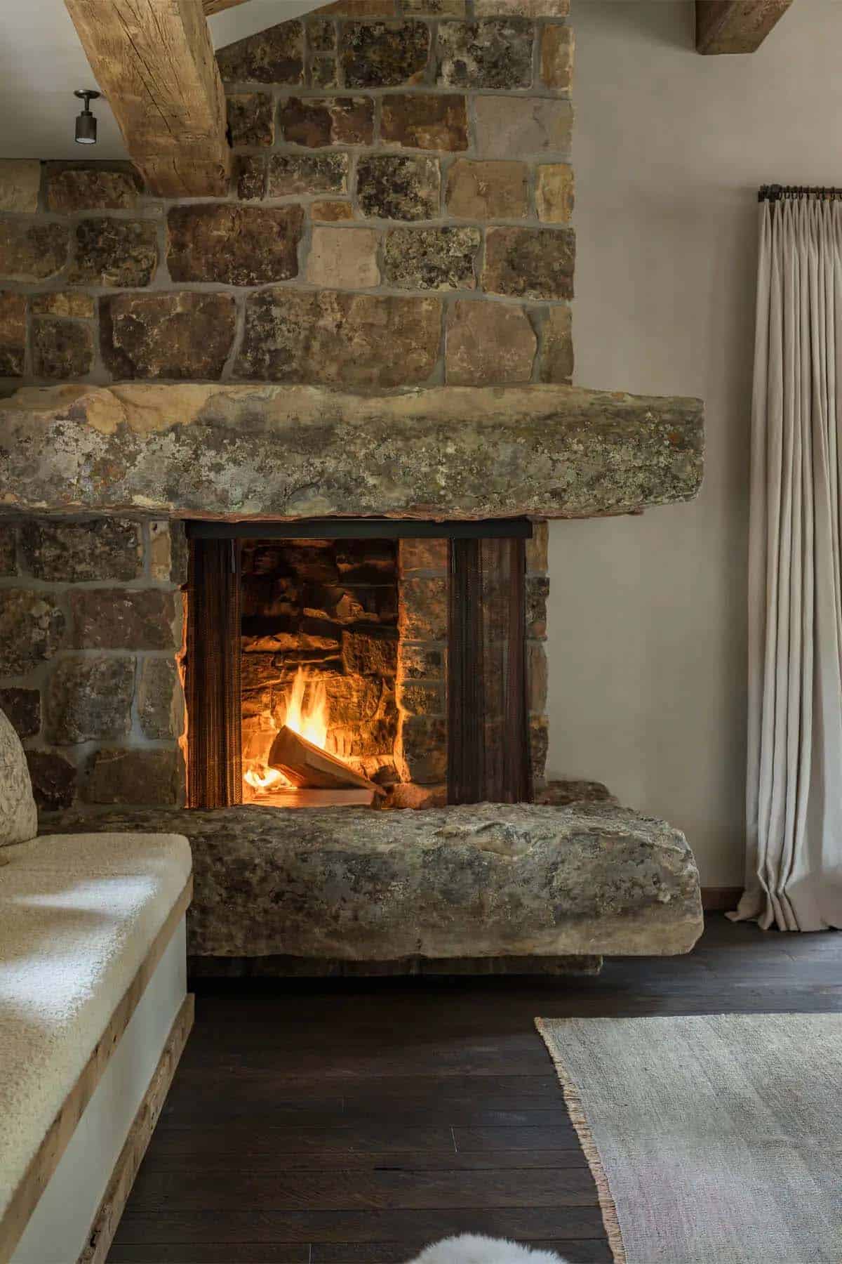 Stone fireplace with thick rustic hearth slab and mesh curtain screen