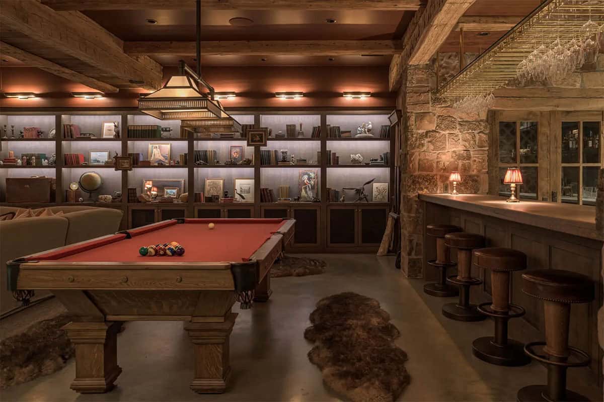 Pool table room with built-in bookshelves and stone-walled bar with stools