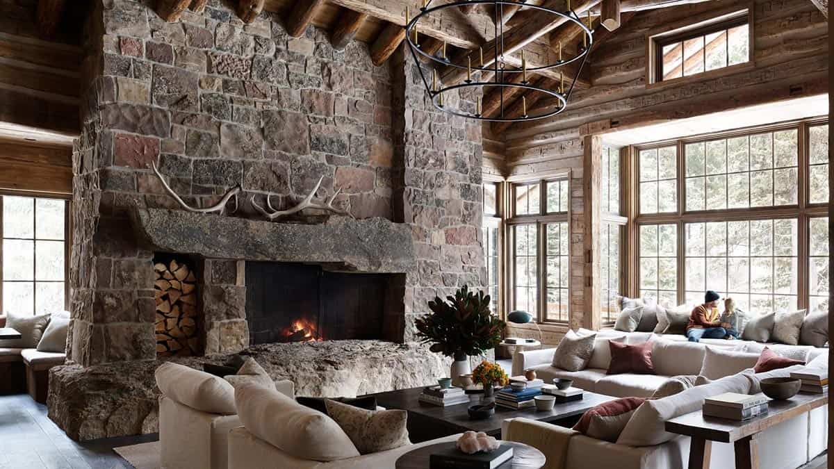 Vaulted great room with massive stone fireplace, antlers, and wraparound windows