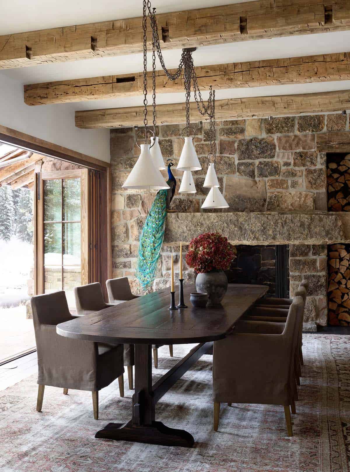 Rustic dining room with stone fireplace, taxidermy peacock, and cone pendant lights