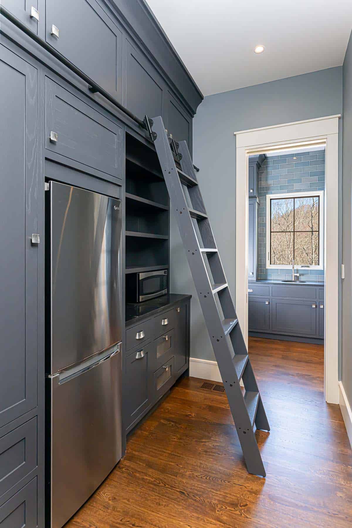 Pantry hallway with sliding ladder and built-in refrigerator