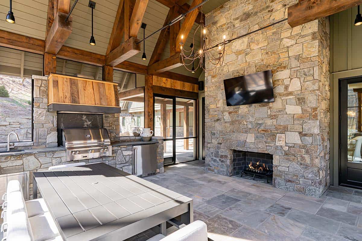 Outdoor living area with stone fireplace and mounted TV
