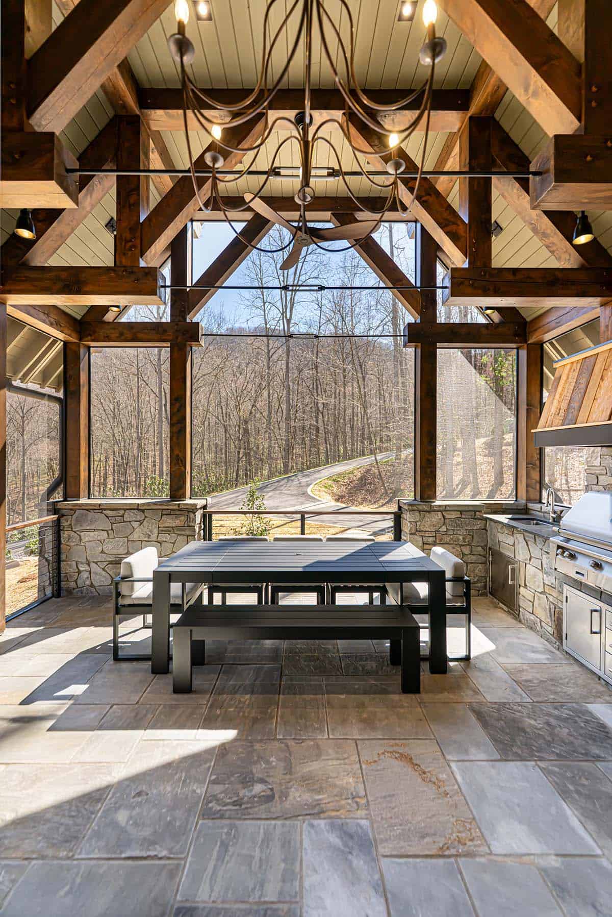 Outdoor kitchen with stone fireplace and forest view
