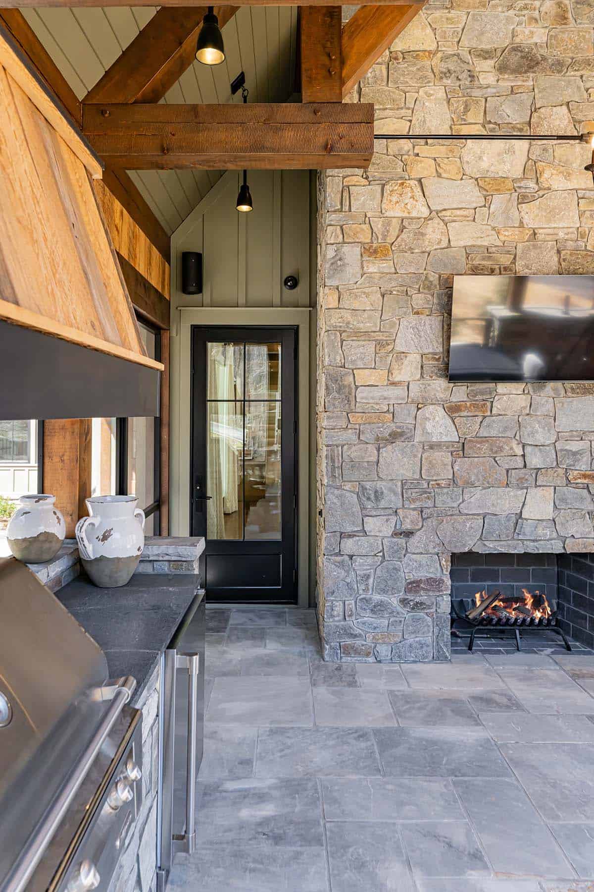 Outdoor fireplace with stone surround and mounted TV