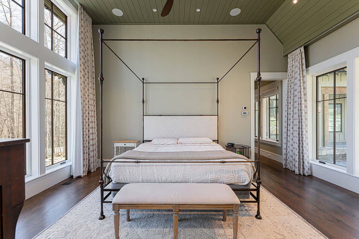 Primary bedroom with iron canopy bed and patterned rug