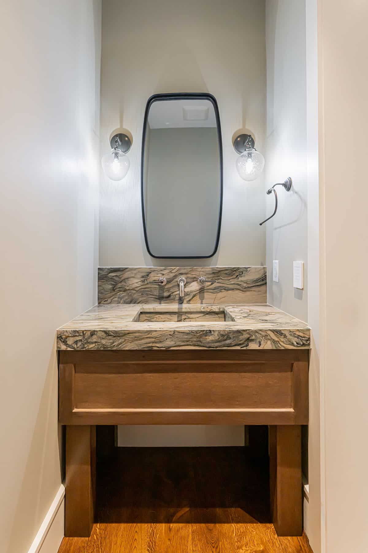 Powder room vanity with marble countertop and wall-mounted faucet